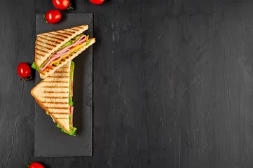 Wandaufkleber Sandwich mit Schinken, Käse, Tomaten, Salat und geröstetem Brot. Draufsicht isoliert auf schwarzem Hintergrund. © dizelen