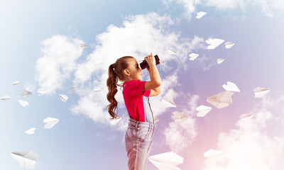 Concept of careless happy childhood with girl looking in binoculars