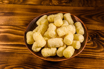 Ceramic plate with corn sticks on wooden table