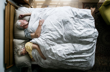 Elderly Caucasian couple sleeping on the bed