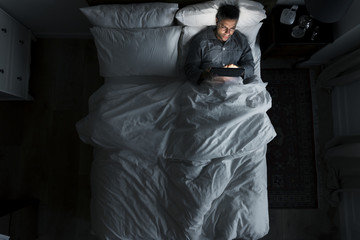 Man on bed using his tablet