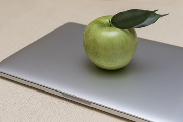 The green fresh Apple lies on the laptop.