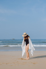 Fototapeta na wymiar Girl in a hat walking along the beach