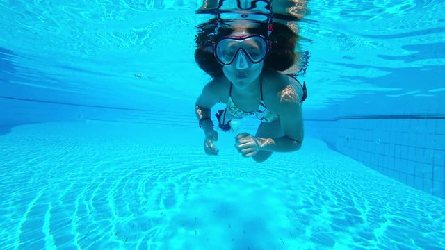 girl teenage swims underwater in the pool