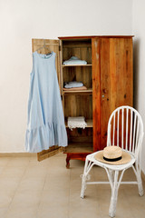 The dress hangs on an antique cupboard with a hat in the bungalow room 