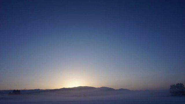 山から昇る朝日　日の出タイムラプス　青空　冬　雪景色