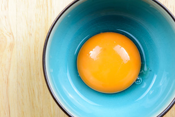 Close up egg yolk in bowl on wooden table, top view