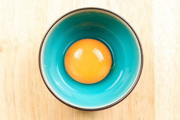 Egg yolk in bowl on wood table, top view