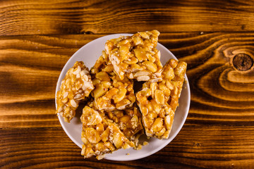Ceramic plate with peanut brittles on wooden table. Top view