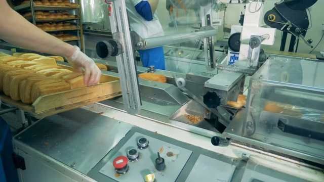 A worker loads puff pastry into a packing machine. 