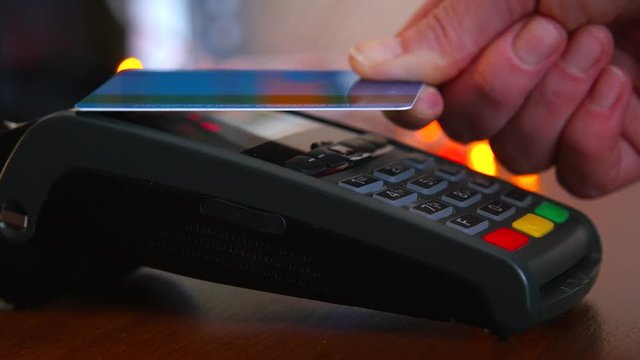 Female hand with a bank card using the terminal for payment. The concept of non-cash payment