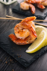 Fried shrimps with lemon on a black table in a restaurant.