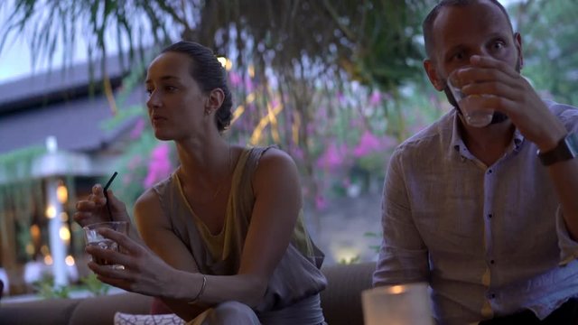 Offended, resentful couple drinking beverages sitting in garden in cafe
