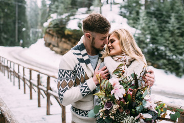 Man hugging woman on wooden bridge in mountain