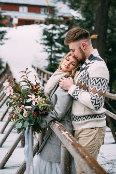 Man hugging woman on wooden bridge in mountain