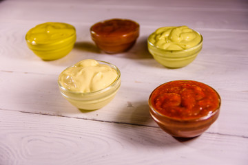 Different sauces in glass bowls on wooden table