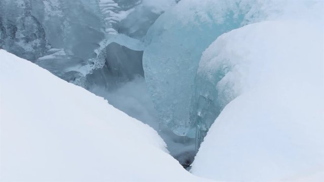 Cold water flowing underneath frozen ice sheets of a small creek