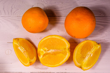 Whole and sliced oranges on a wooden table. Top view