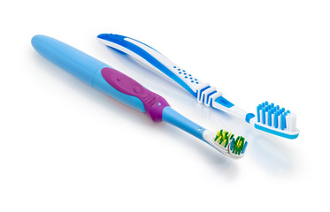 Electric and conventional toothbrushes on a white matte surface