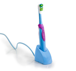 Standard electric toothbrush in charging base on a white background