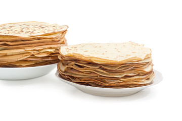 Thin round pancakes on two white dishes closeup