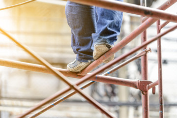 Industrial worker labourer on scaffolding, construction site.