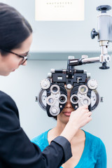 Optometrist and woman at eye examination with phoropter