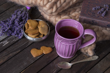 on a wooden table lavender, plaid, book, purple tea mug, and cookies