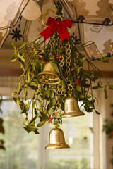Decorated chandelier with mistletoe and golden bells.