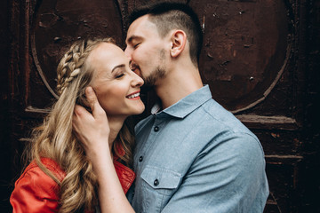 An attractive guy kisses and hugs his beloved beautiful girl, and she smiles. Love story