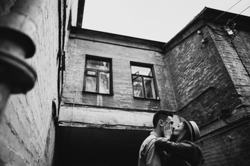 The girl passionately kisses her beloved guy outdoors against the background of the old building. Black and white photo