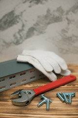Fototapeta na wymiar Set of construction and repair tools, small house on wooden board background, top view, closeup