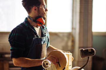 Carpenter begining working on woodworking machines in carpentry shop.
