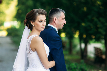 Young couple, bride and groom walking and enjoying their wedding day. Sunshine. Summer