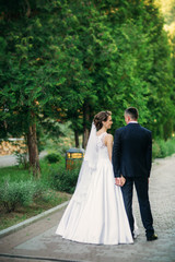 Naklejka premium Young couple, bride and groom walking and enjoying their wedding day. Sunshine. Summer