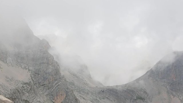Mountain cliff landscape seen through semitransparent scud clouds