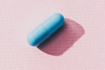 close up view of blue medicine on pink surface