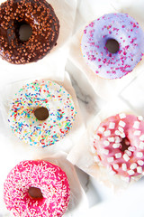 Various donuts on a marble pattern background. Top view shot. Sweetness, happiness conception.