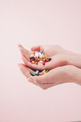 partial view of woman holding pills in hands isolated on pink