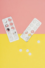 top view of pills isolated on pink and yellow background