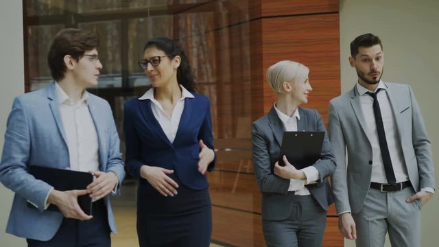 Group of young business people talking and walking in office lobby