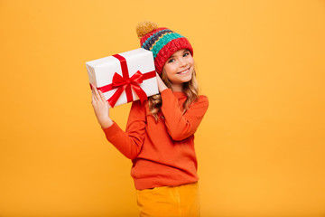 Smiling Young girl in sweater and hat holding gift box