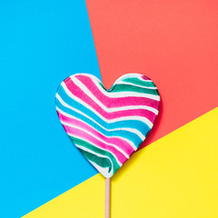 Lollipops rainbow candy as heart on colorful paper. Funny concept. Top view. Square image.