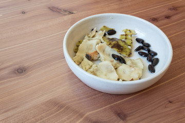 Wood background with bowl aligned right, pieces of skin and seeds of an eaten cherimoya fruit, Annona cherimola, copy space, horizontal aspect