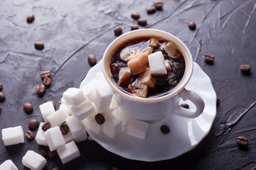 Sugar addict. Heap overabundance of sugar in a cup of coffee on a black table with scattered coffee beans - obrazy, fototapety, plakaty