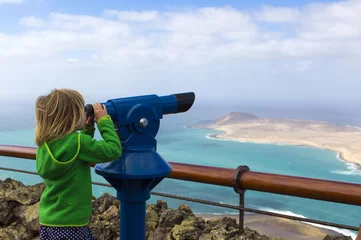 Fotobehang Girl looking through telescope at the island and the sea, Mirador del Rio, Lanzarote   © pikselstock