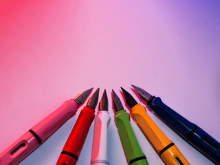 A collection of fountain pens on colored background