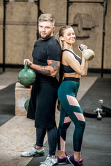 Portrait of a young athletic couple in black sports wear standing in the gym