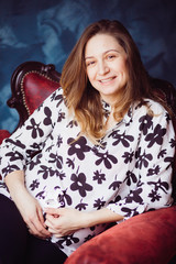 Fototapeta premium The pregnant girl sitting on the chair