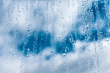 Naklejka na ściany i meble Water drops of rain on a window glass, clouds in background